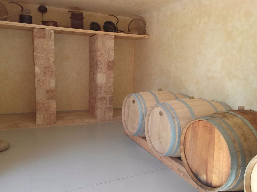 lying wine barrels in a row on the wood panel at 'Piperis Winery' cellar